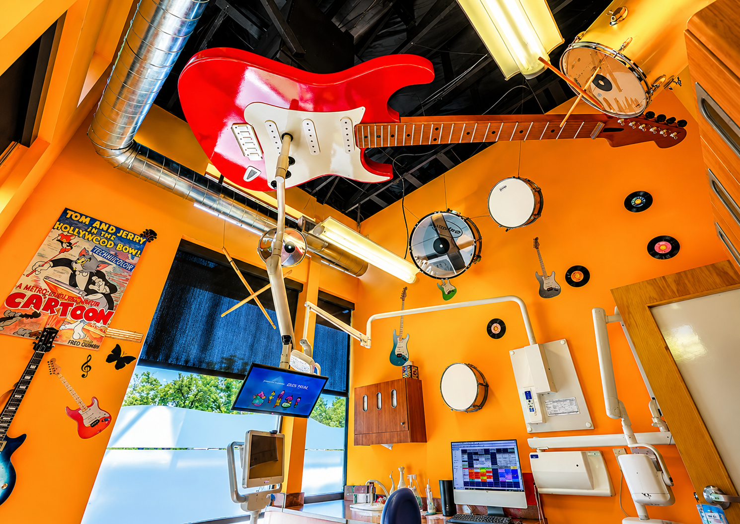 Rock-and-roll themed dental room with a giant red guitar and drums on the ceiling
